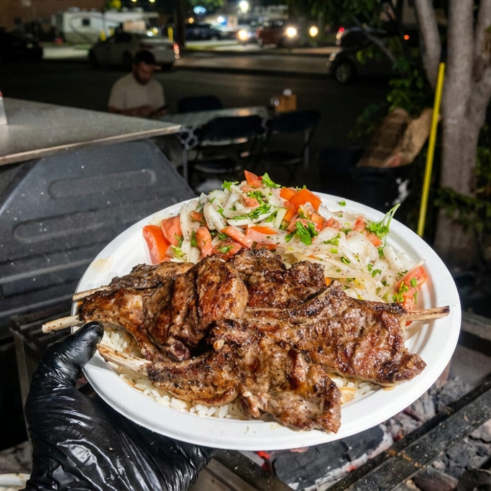 Plate of grilled meat skewers over rice with salad, held beside an outdoor charcoal grill at night.
